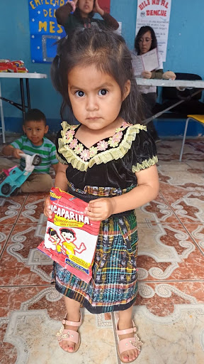 A young girl holds a package of Incaparina while standing indoors.